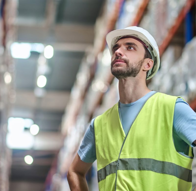 Man in overalls with hands on belt looking up